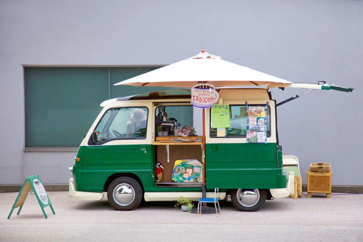 日よけの傘を広げた緑のキッチンカー
